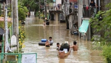 Residents wade through floodwaters left by torrential rains of Typhoon Doksuri in Calumpit, Bulacan province on July 29, 2023.